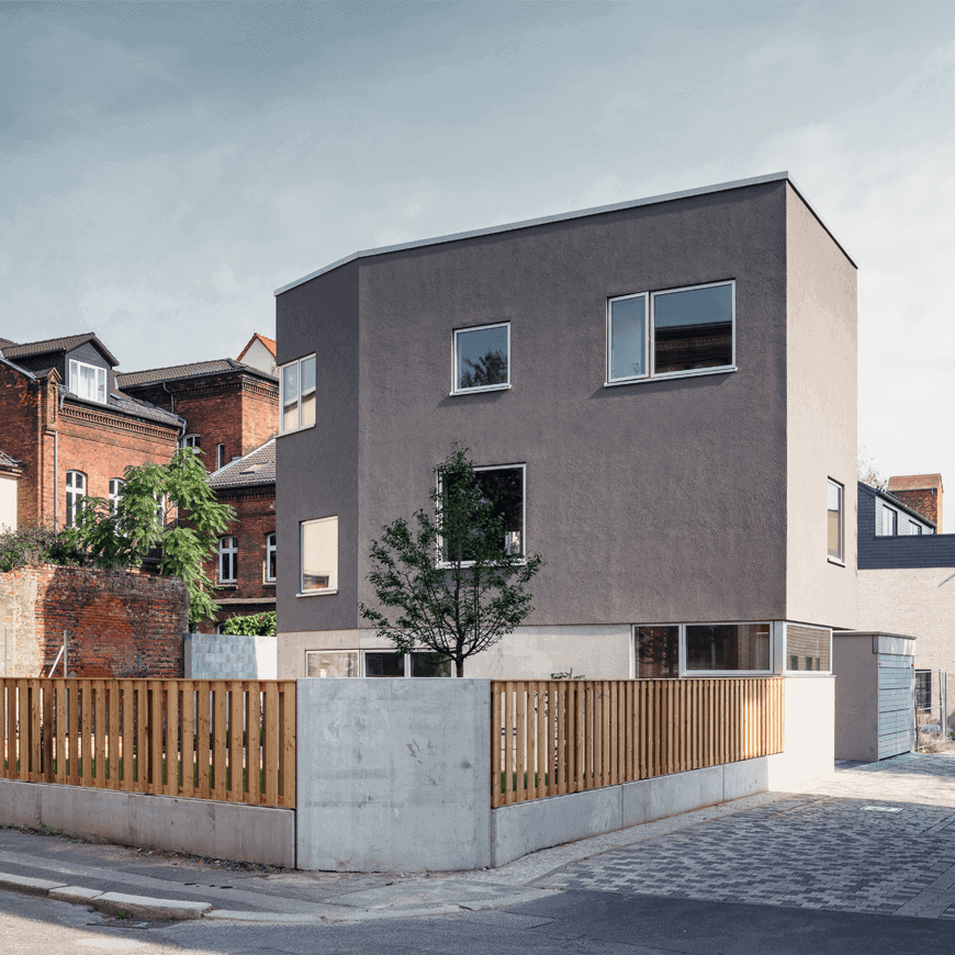 Modernes Einfamilienhaus mit grauer Putzfassade, Flachdach und Holzzaun